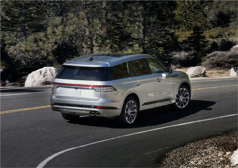 A 2023 Lincoln Aviator® Grand Touring model is shown being driven on a tight turn of a mountain road