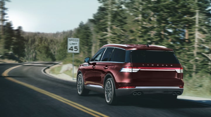 A 2024 Lincoln Aviator® SUV is being driven on a winding mountain road | Stivers Lincoln in Waukee IA