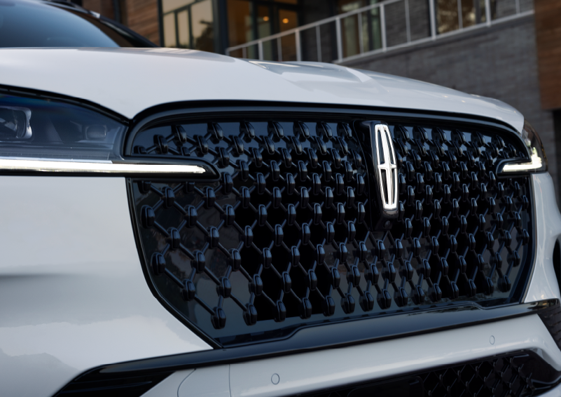 The black grille of a white 2025 Lincoln Aviator® SUV is shown with its fog lights on. | Stivers Lincoln in Waukee IA