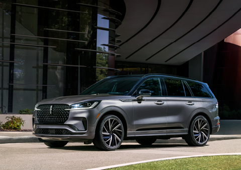 A gray 2025 Lincoln Aviator® SUV is parked outside a modern building showcasing the driver’s side of the vehicle. | Stivers Lincoln in Waukee IA