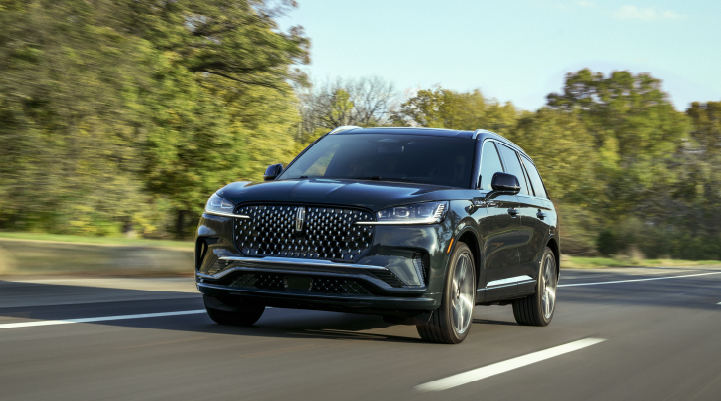 A 2025 Lincoln Black Label Aviator® SUV is being driven down a road lined with trees. | Stivers Lincoln in Waukee IA