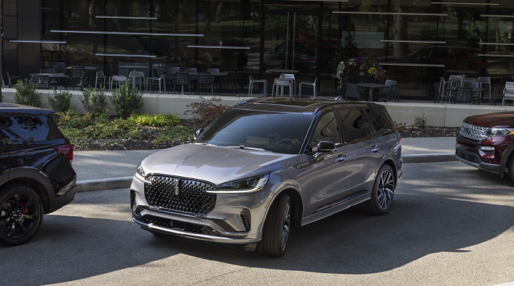 A gray 2025 Lincoln Black Label Aviator® SUV is shown in the process of parallel parking. | Stivers Lincoln in Waukee IA