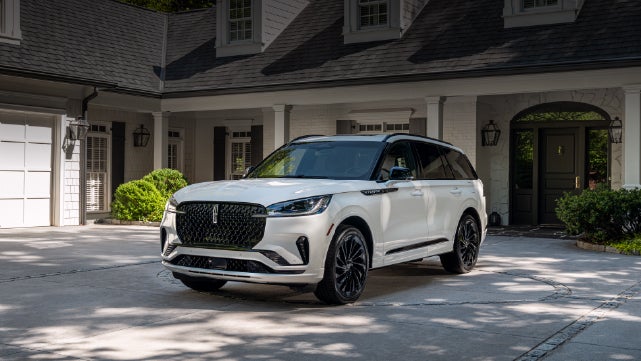A white 2026 Lincoln Aviator® SUV is parked in the driveway of a luxury home. | Stivers Lincoln in Waukee IA
