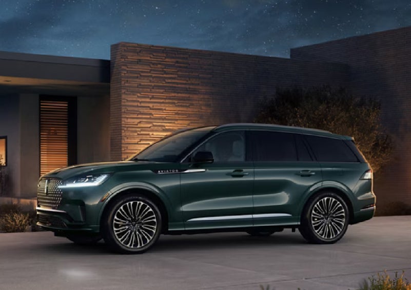 A green 2027 Lincoln Aviator® SUV is parked outside a contemporary home. | Stivers Lincoln in Waukee IA