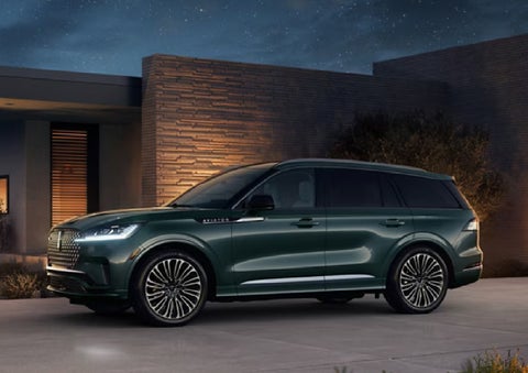 A green 2027 Lincoln Aviator® SUV is parked outside a contemporary home. | Stivers Lincoln in Waukee IA