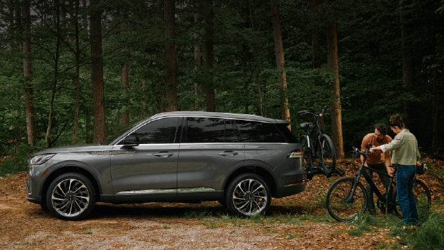 A father and son load e-bikes on a bike rack attached to a 2027 Lincoln Aviator® SUV. | Stivers Lincoln in Waukee IA