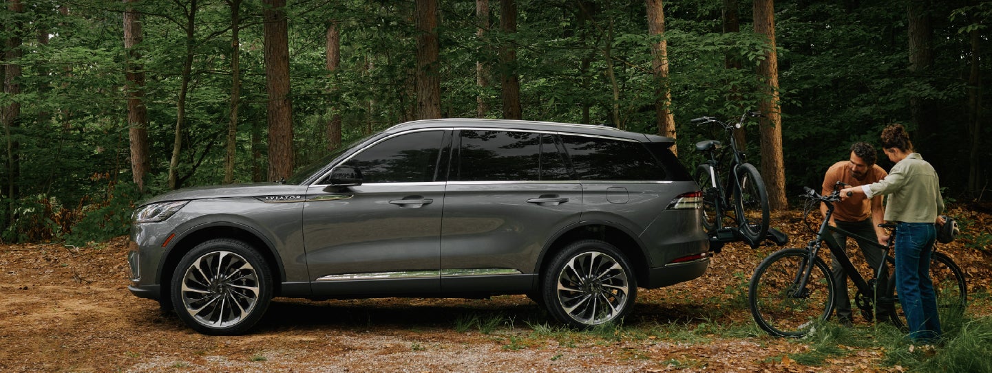 A father and son load e-bikes on a bike rack attached to a 2027 Lincoln Aviator® SUV. | Stivers Lincoln in Waukee IA
