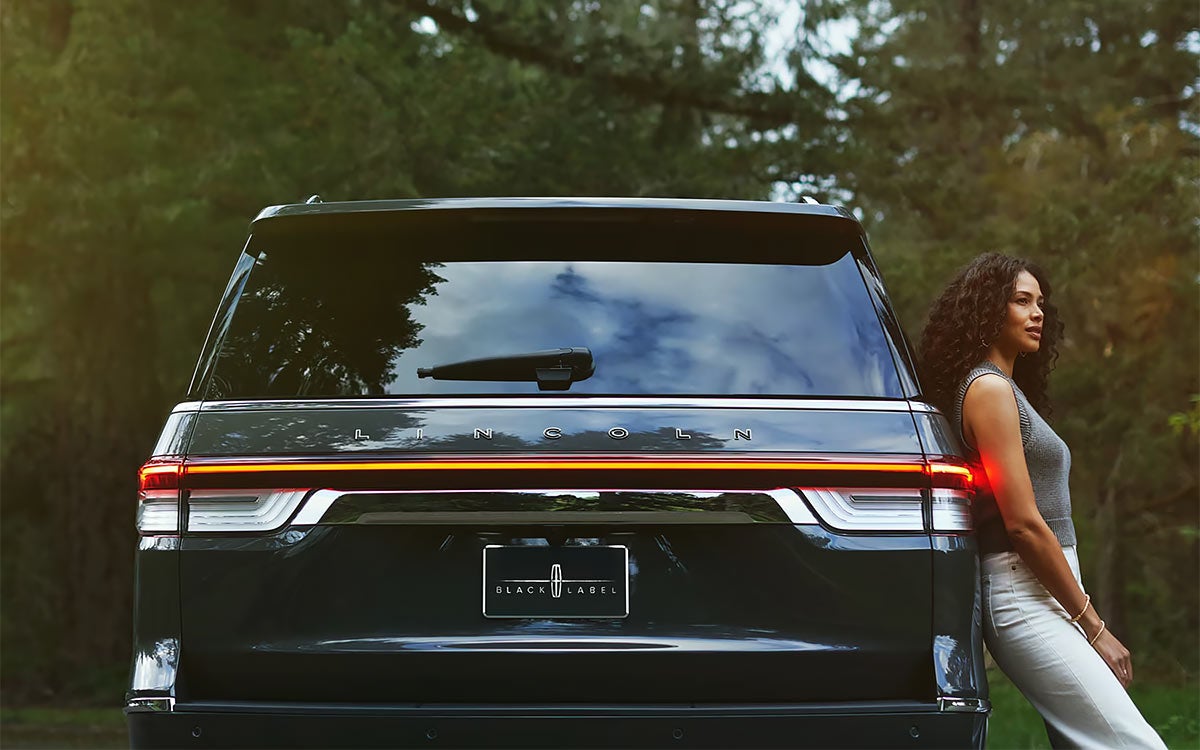 A woman leaning against a Lincoln Navigator® Black Label™ model.